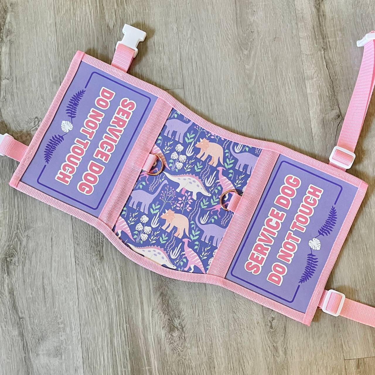 A brown and pink service dog vest with a center panel with deer artwork and florals. The side panels read: "Service dog, distractions may distress handler, give us space"