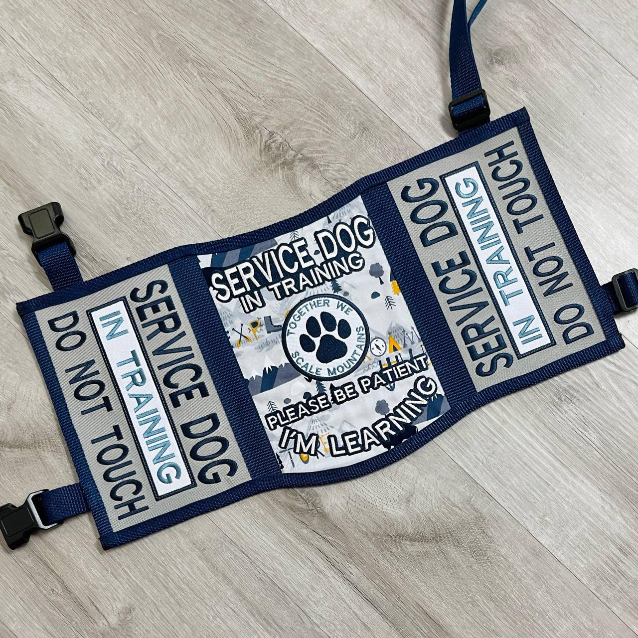 A God of War videogame themed service dog vest. It is gold and dark grey/green with black accents. The panels read: "Medical alert service dog, It is the nature of a thing that matters" "Stop! Do not distract us on our journey. Medical alert service dog"